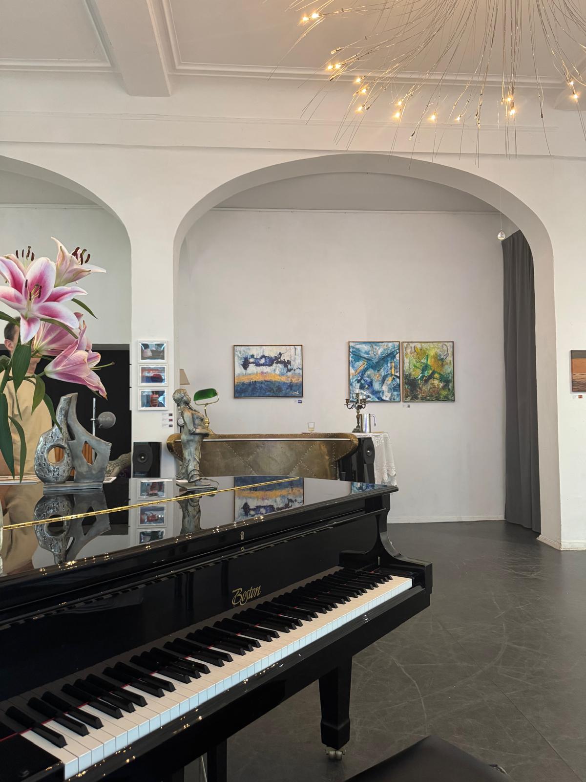 Gallery interior in Berlin with a black grand piano and Nili Stein's paintings on the wall
